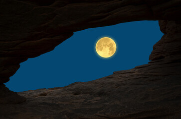 Big full moon in blue sky in cave entrabce view