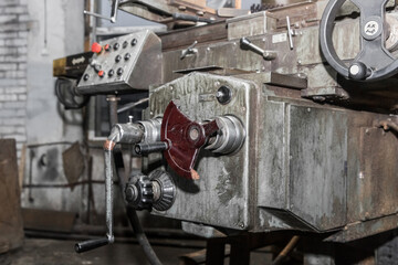 Handle of an old milling machine on the background of the control panel in the workshop of an industrial plant