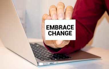 Closeup on businessman holding a card with text EMBRACE CHANGE, business concept image.