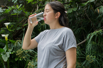 Mujer toma agua de un vaso.