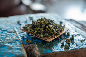 Beautiful and traditional envrionment of old wooden table and Chinese green tea on flat container and some leaves spread on the table