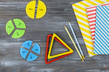 Multicolored fractions, blocks, notebook on a gray wooden table. Back to school, fun math, games for kindergarten, preschool education.