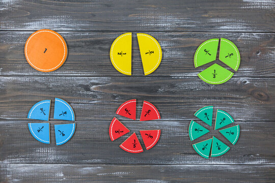 Multicolored fractions on gray wooden table. Back to school, fun math, games for kindergarten, preschool education.