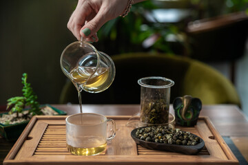 Beautiful indoor scene were hand is holding tea pot and pouring Chinese tea on the cup