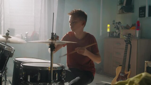 Teen drummer rehearsing in sunlit room