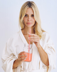Girl with a drink and a straw in home clothes.