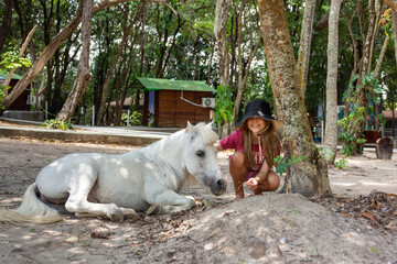 Criança acariciando cavalo branco deitado em paz