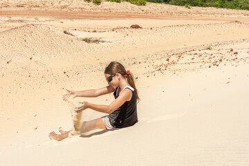 Fototapeta na wymiar Criança se diverte com areia em dia ensolarado