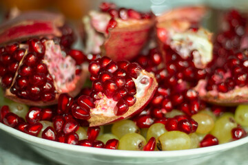 Pomegranate in a plate. Delicious fruit. Red fruits with seeds.