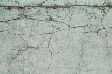 The texture of an old concrete wall with cracks and faded paint. Destruction of the outer wall under the influence of time and weather conditions.