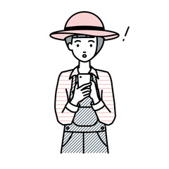 立ってスマートフォンを操作して何かに気づいて驚いた農家の女性