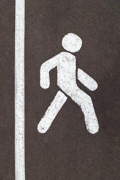 White walking person street sign on grey city asphalt road with vertical stripe