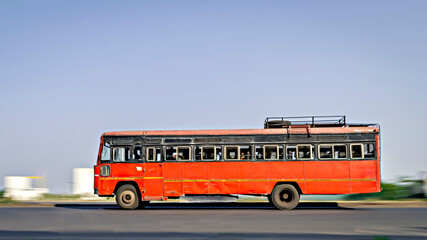 Background blur, pan image of non air-conditioned red intercity bus in Maharashtra, speeding on the...