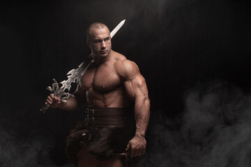 Ferocious muscular ancient warrior barbarian with fantasy sword on black background - obrazy, fototapety, plakaty