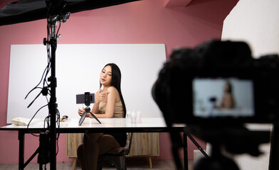 Fototapeta na wymiar Beautiful asian woman blogger is showing how to make up and use cosmetics. In front of the camera to recording vlog video live streaming at home.Business online influencer on social media concept.