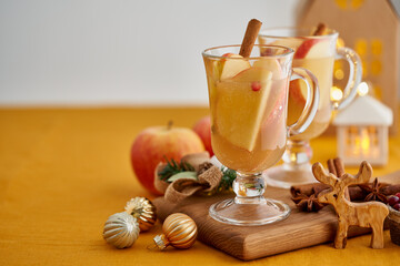 Two glasses of hot christmas winter apple gluhwein. Alcohol white mulled wine with cinnamon, cranberry. Apple cider. Selective focus, blurred christmas decor background, copy space