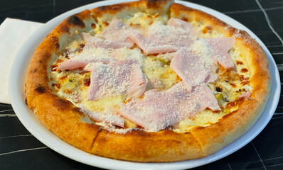 Close-up on a restaurant table pizza with prosciutto cotto and taleggio cheese