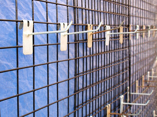 row of grey steel hook hanging on metallic vertical grid for show product