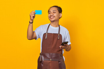 Portrait of smiling handsome barista showing credit card to pay and holding smartphone