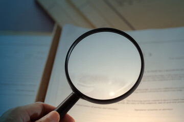 a hand holding magnifying glass look for information on file.