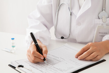 close up of doctor writing medical records on desk.