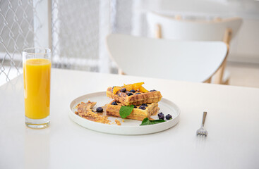 Delicious Belgian waffles with berries and fruits and a glass of juice.