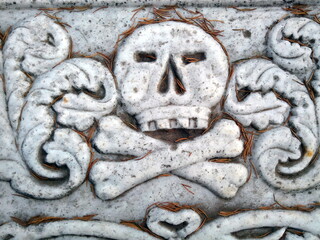 Human skull and crossbones on an old tomb. Memento mori (Latin for "Remember that you will day") symbol. 