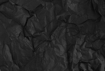 Black crumpled wrinkled paper pattern surface texture background.
