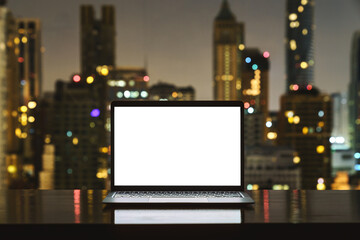 laptop computer on workspace white blank screen display city on