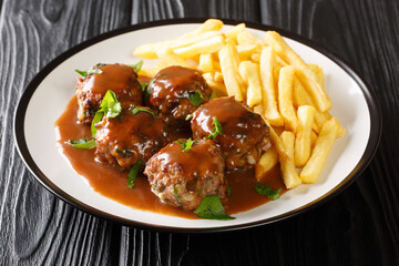 Belgian Boulets sauce lapin meatballs in apple gravy and French fries closeup in the plate on the table. Horizontal