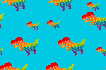Fototapeta na wymiar Seamless pattern. Toy pop it in the shape of a dinosaur on a turquoise background.