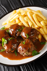 Boulets liegeois is a popular dish served all over Belgium made of meatballs swimming in an apple and onion gravy served with fries closeup in the plate on the table. Vertical