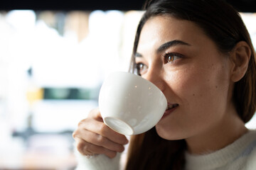 young woman drinking coffee and using smart phone