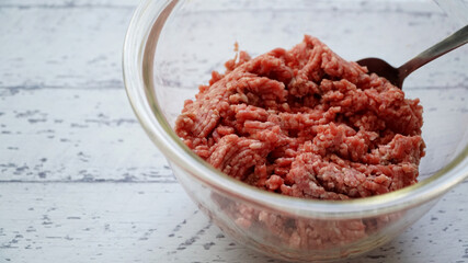 ガラス製のボールに入った生の合い挽きに肉とスプーン