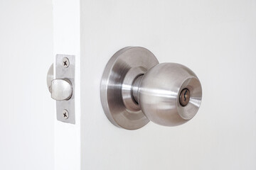 Stainless door knob with key hole on white wooden door 
