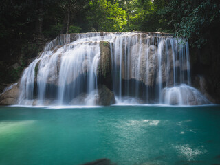 Scenic view of Erawan Waterfall breathtaking smooth flowing water stream with crystal clear turquoise lagoon in lush rainforest. Kanchanaburi, Thailand. Long exposure.