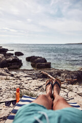 Man sunbathing on a rocky sea ocean beach.