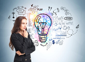 Attractive businesswoman is standing near colourful sketch with light bulb