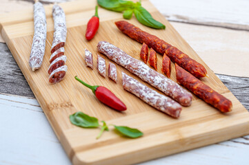 assorted mini salami with vegetables on wooden board