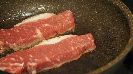 フライパンで焼かれているステーキ