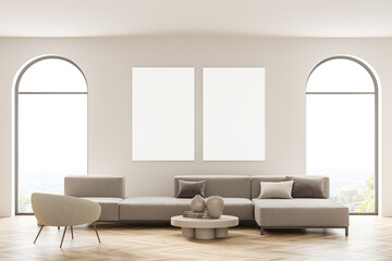 Light living room interior with sofa and armchair near window, two posters