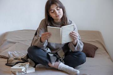 Obraz premium Young woman reads a book while sitting in bed.