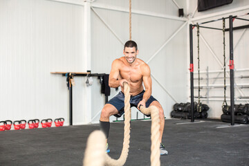 Plakat Men with battle ropes exercise in the fitness gym