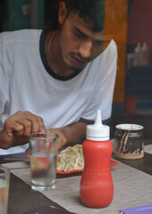 View of a young guy eating fast food in the cafe seen through the window glass. 