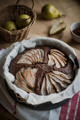 Rustical chocolate cake with pear, traditional winter and autumn desert with seasonal fruit, homemade pastry, served on the plate powdered with cocoa