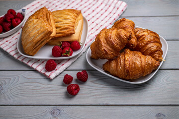 Delicious fresh pastries with raspberries in a white plate on a wooden table.
