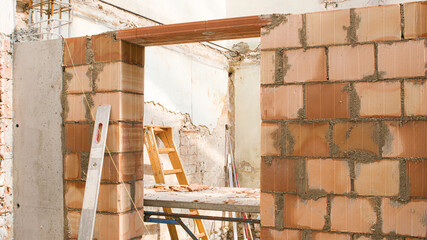 brick wall of a construction site with a ladder in the background