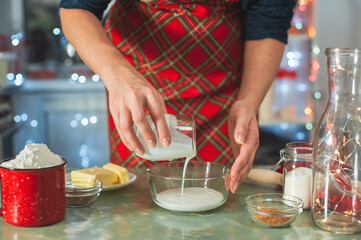 Christmas cooking. Women's hands prepare dough in glassware in a decorated kitchen.