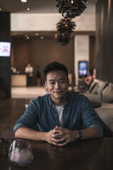 Asian young handsome man sitting in coffee shop and smiling. Chinese guy, millennials life, lifestyle in the big city, Modern Asia, coffee break