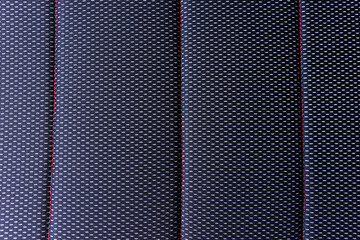 Part of textile car seat cover. Dark car seat cover with red stitching
